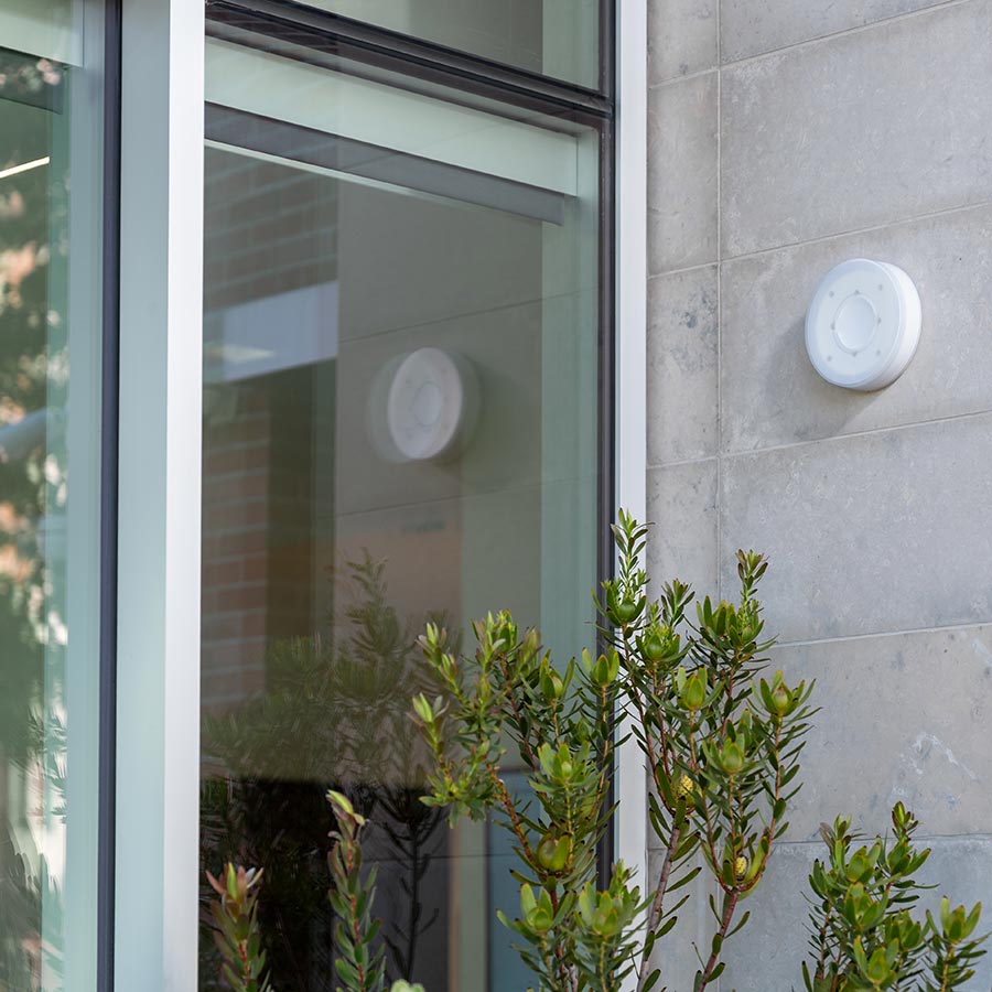 Circular alarm device mounted on an exterior building wall